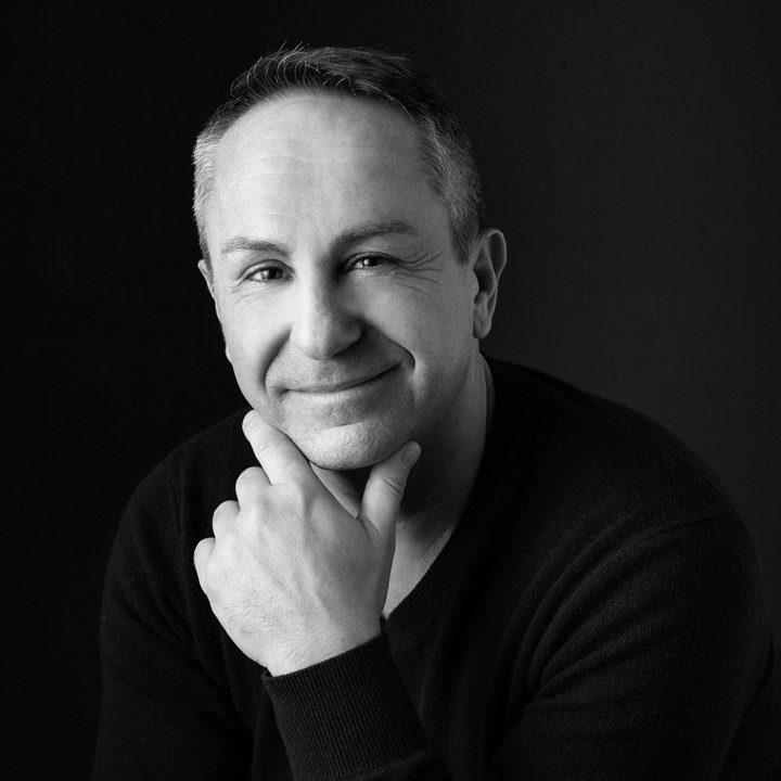 Portrait de Marc Pujol, souriant, en pull noir